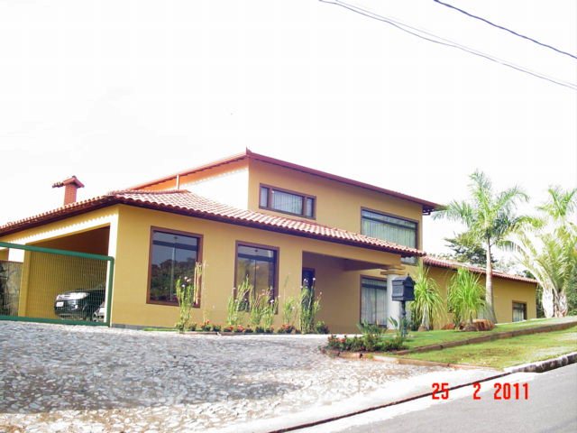 Fachada em tom ocre com telhado cerâmico da residência José Maria