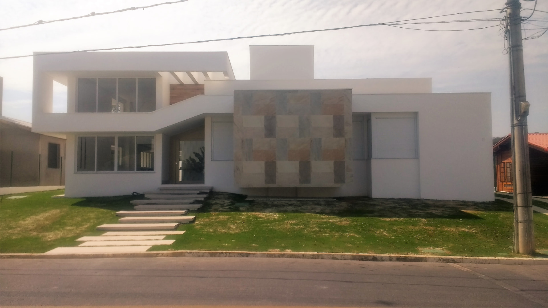 Casa branca de linhas retas com painel de pedra natural no Mont Serrat